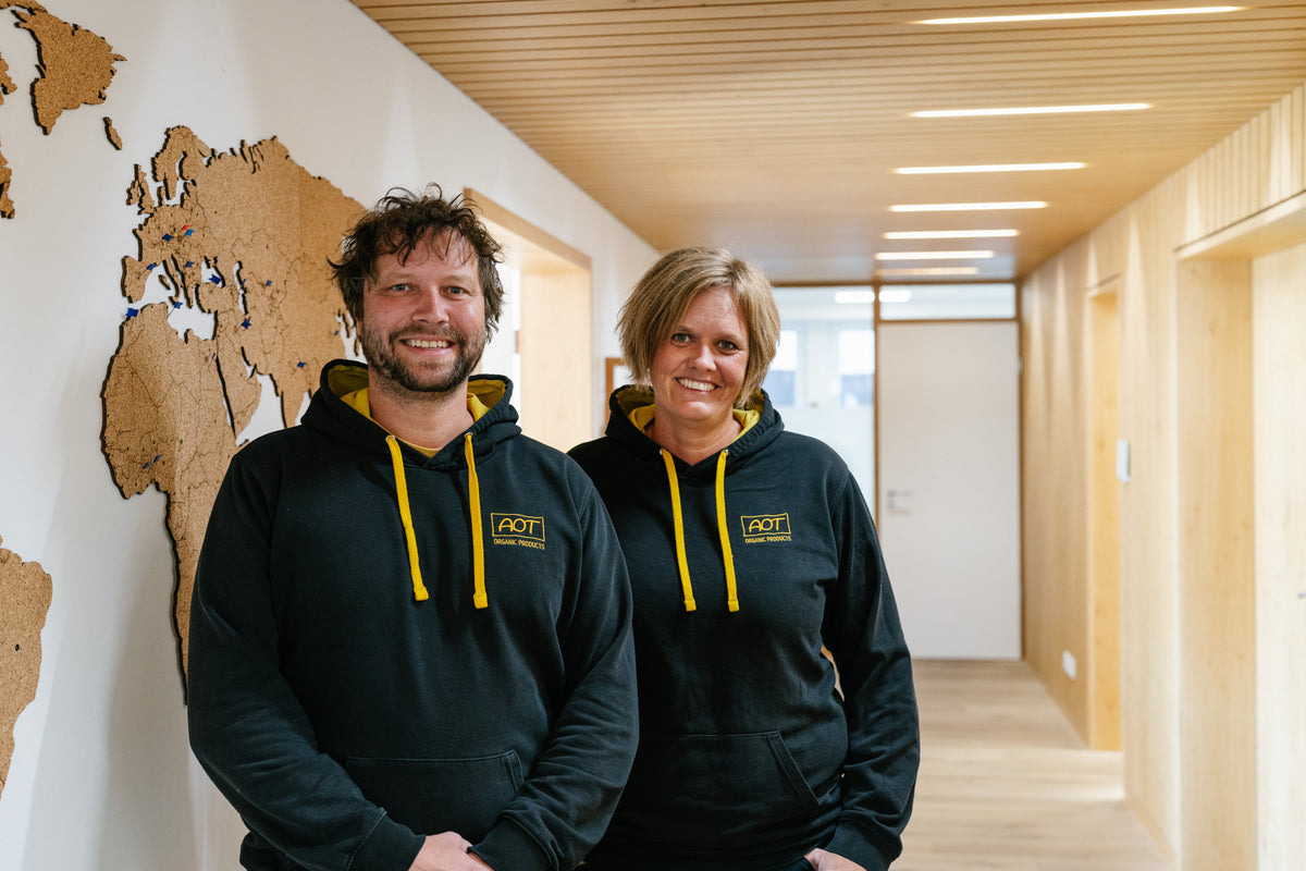 Two AOT employees in company hoodies in the corridor in front of a world map